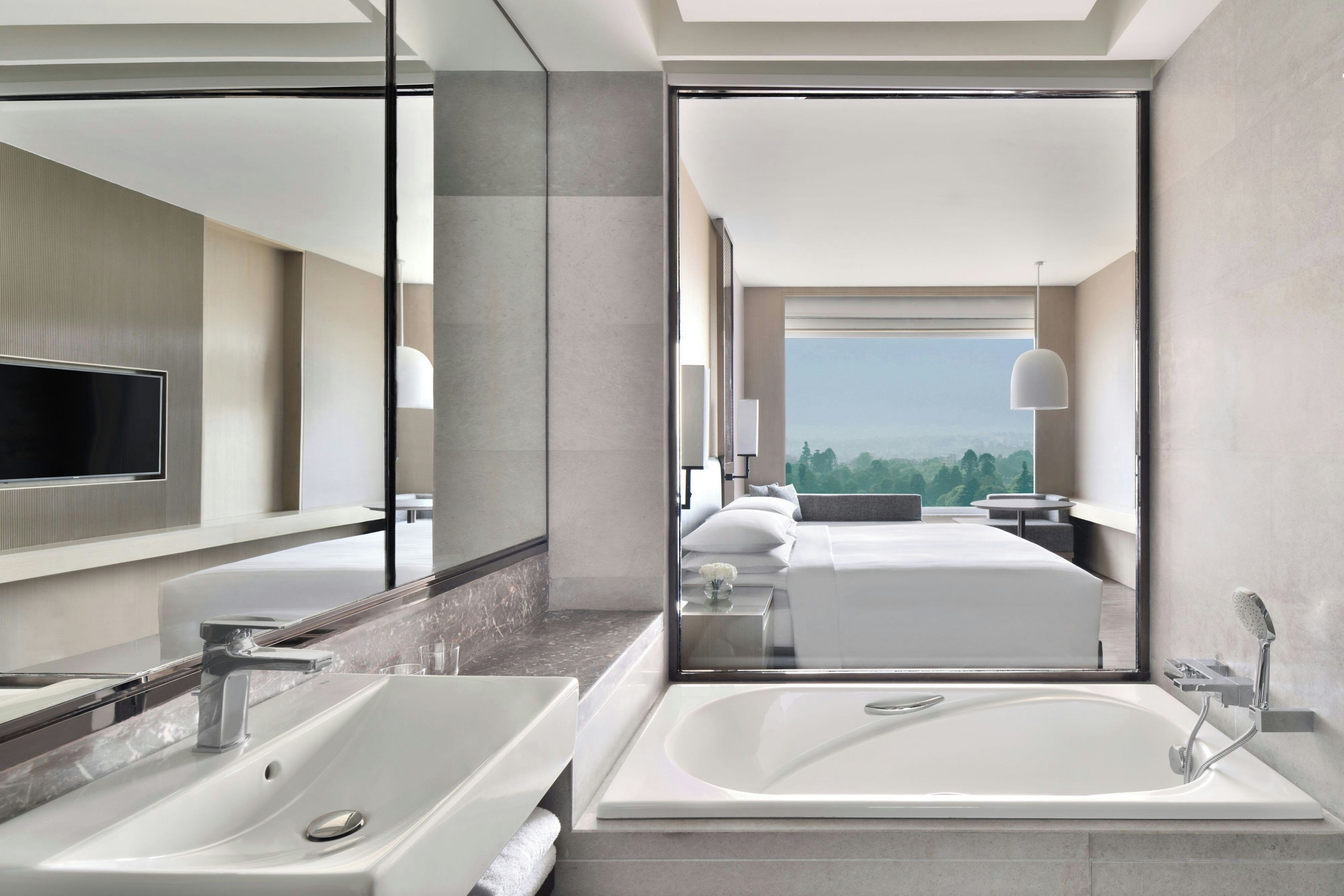 Un baño moderno con un espejo grande, una bañera y un lavabo.