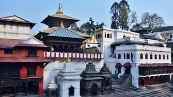 A traditional building with multiple levels, a central pagoda-like structure, and a staircase leading to an upper level.