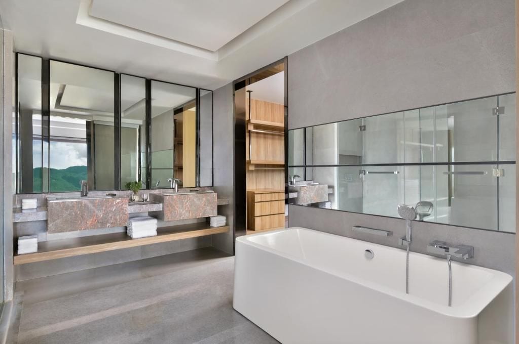 Un baño moderno con una bañera amplia, lavamanos doble y un espejo grande.
