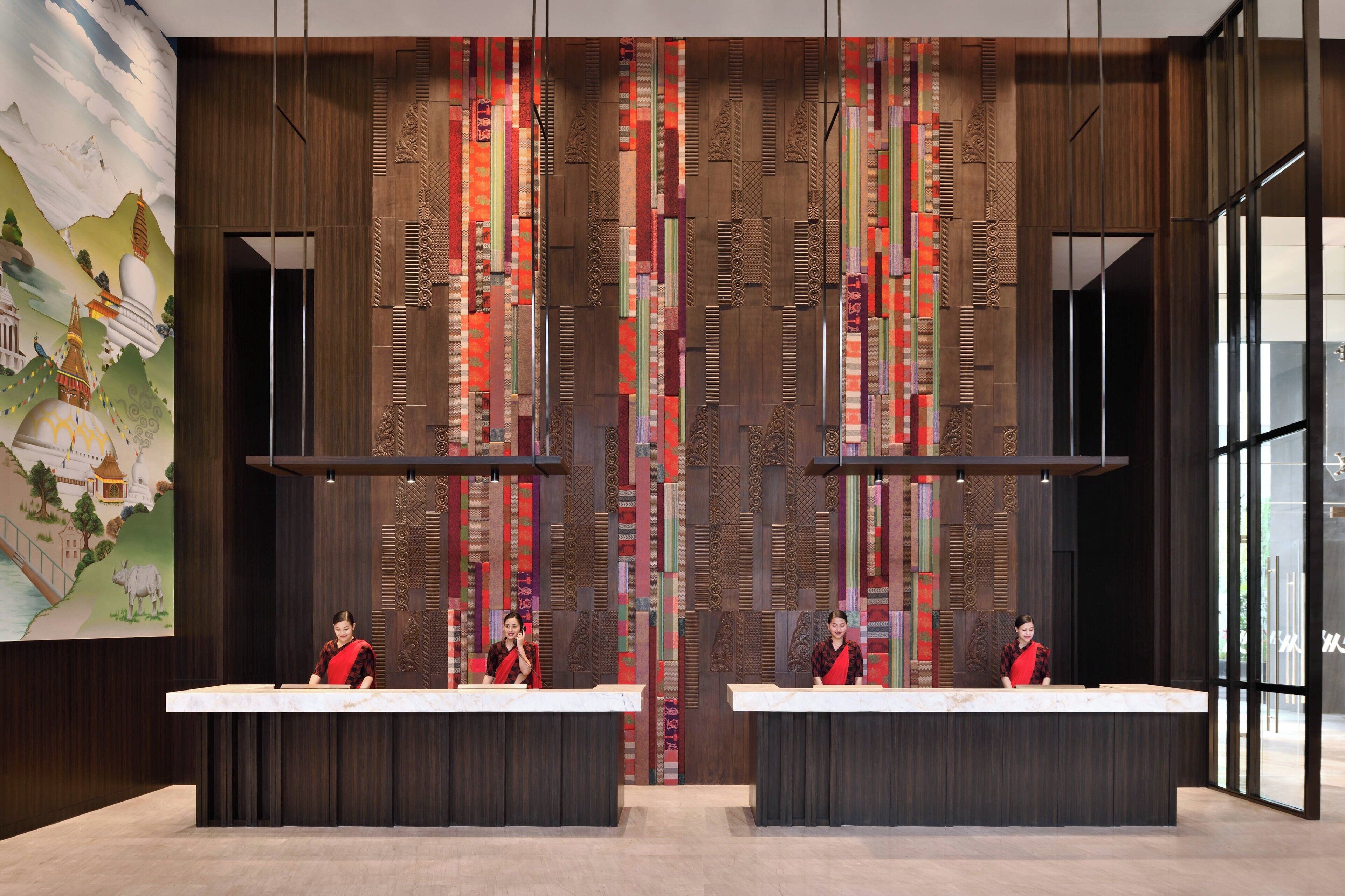 A reception area with two counters, a large mural on the left, and a patterned wall in the center.