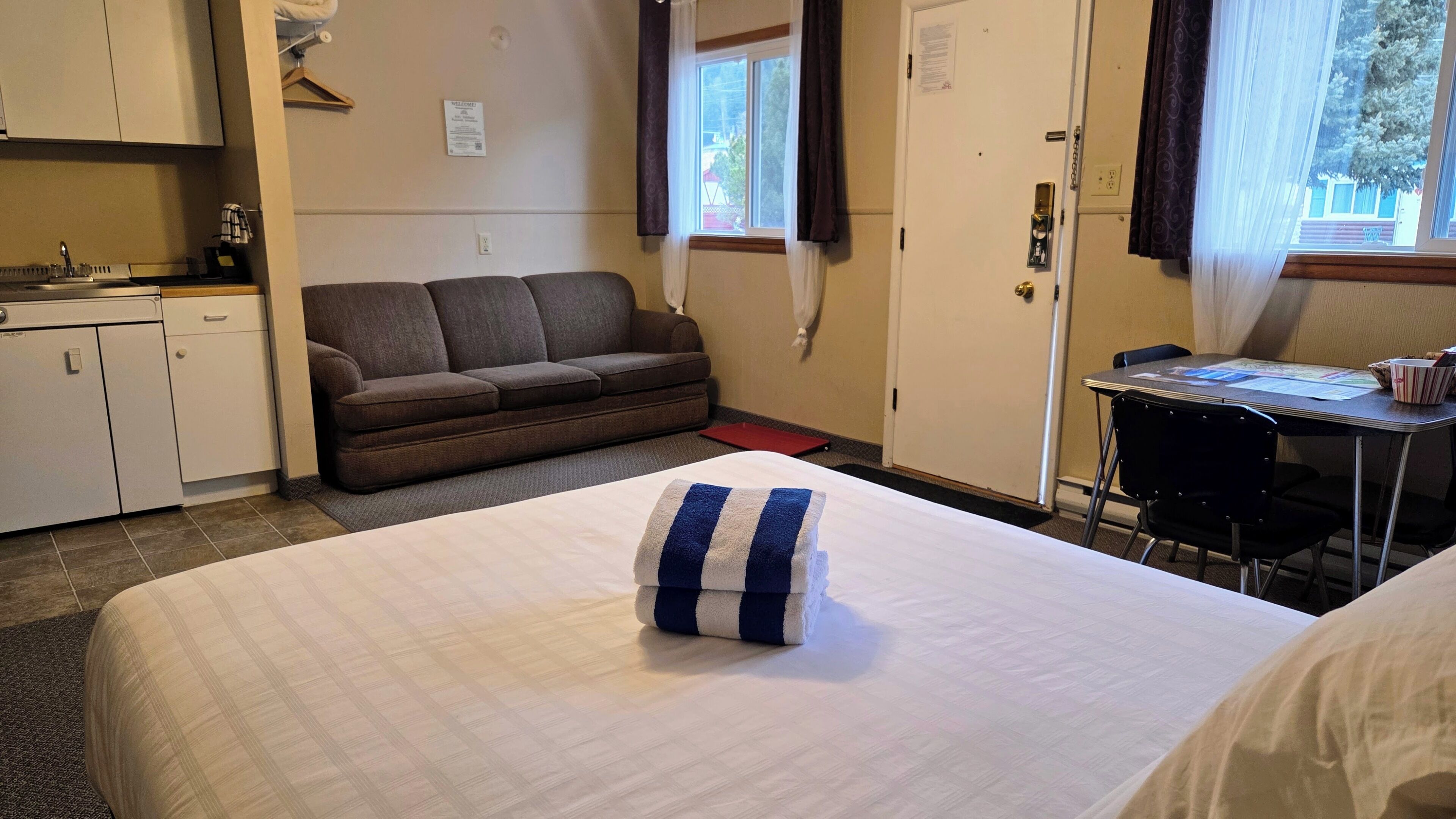Una camera d'albergo con un letto, un divano, una scrivania e un angolo cottura.