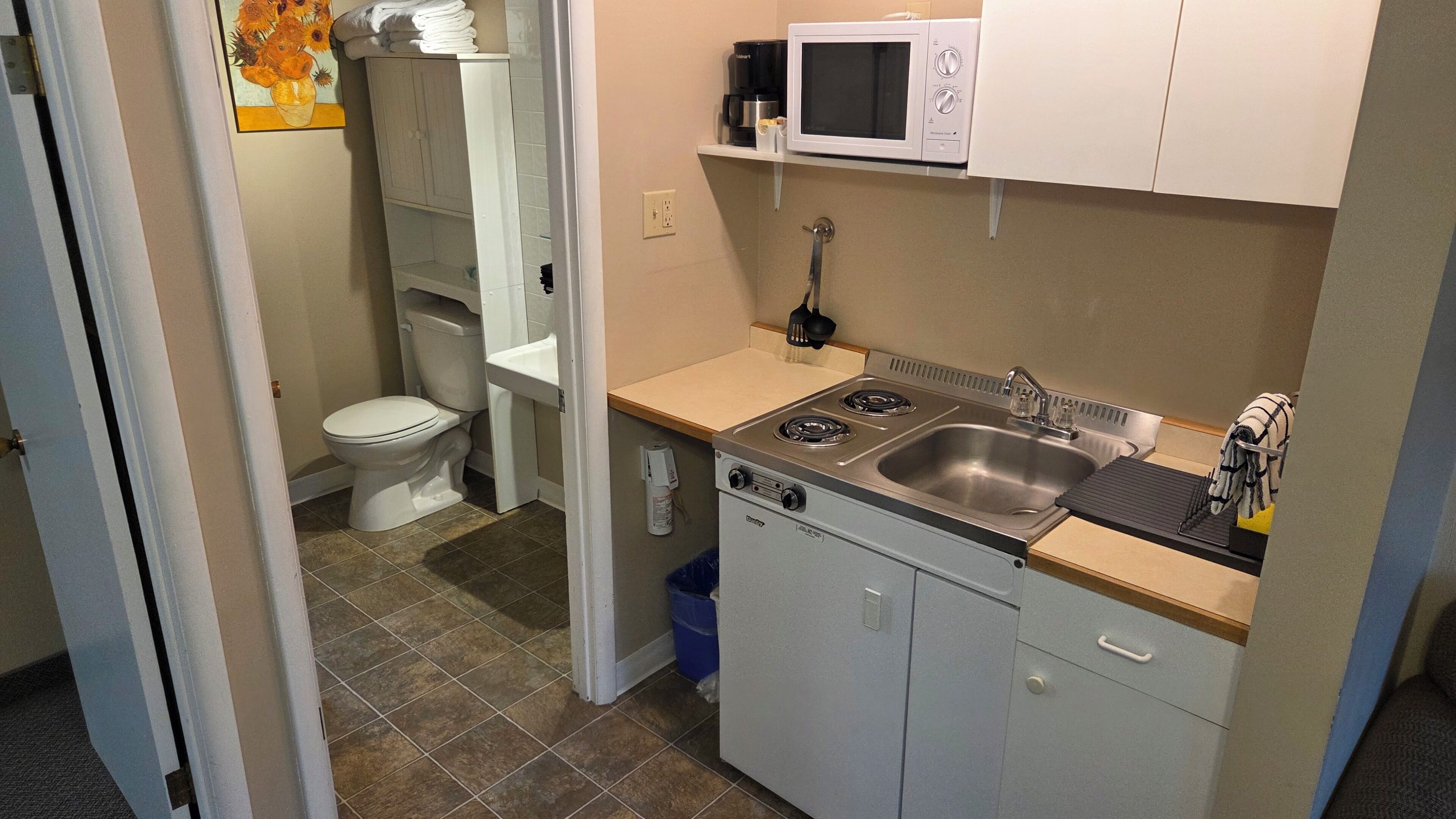 Una cocina compacta con estufa, pileta y microondas.