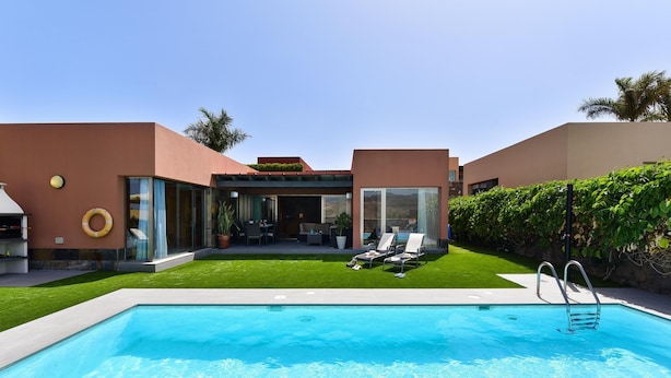 A modern pool area with a clear blue pool, lounge chairs, and a well-maintained lawn. - Salobre Golf Villas - Holiday Rental Par 4 - 8 (San Bartolomé de Tirajana)
