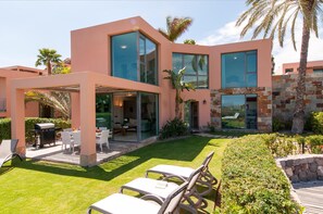 A modern house with a patio, outdoor seating, and a stone wall. - Los Lagos 5- Holiday Rental Salobre Golf (San Bartolomé de Tirajana)