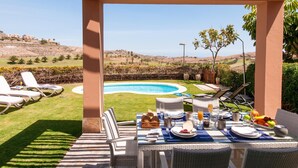 A patio with a pool, outdoor seating, and a table set for breakfast. - Los Lagos 5- Holiday Rental Salobre Golf (San Bartolomé de Tirajana)
