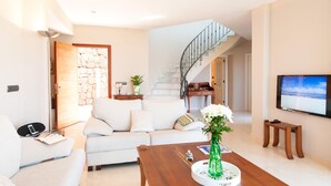 A modern living room with a sofa, coffee table, and a TV mounted on the wall. - Los Lagos 5- Holiday Rental Salobre Golf (San Bartolomé de Tirajana)