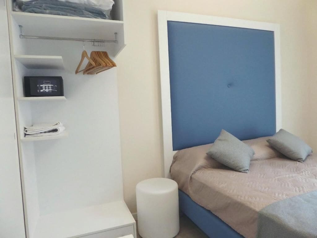 A bedroom with a bed, a wardrobe, a bedside table, and a nightstand.