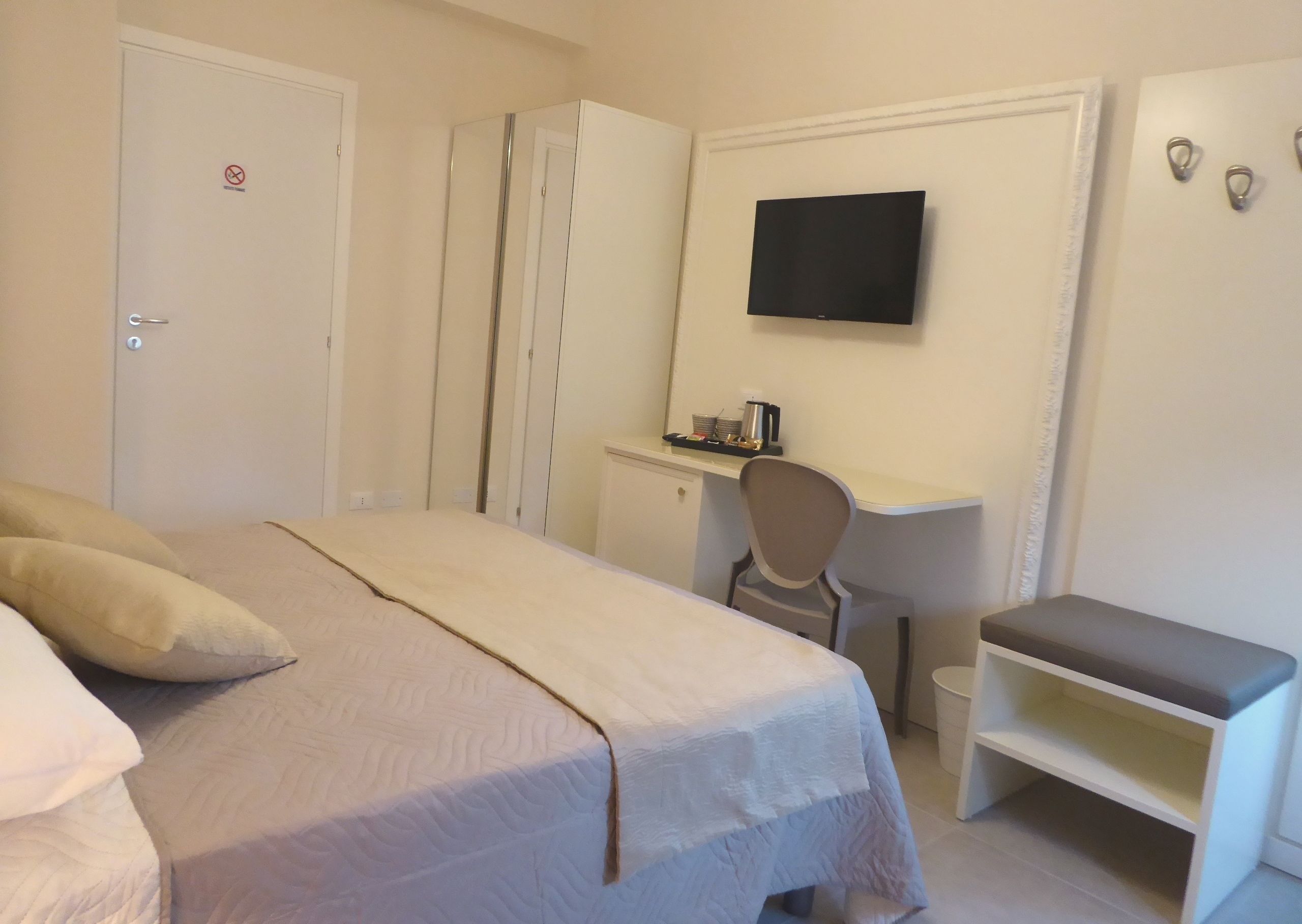 A bedroom with a bed, a desk, a chair, and a TV.