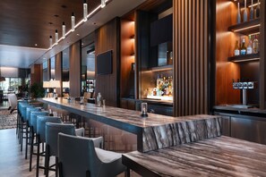 A modern bar area with a marble countertop, bar stools, and a wine display. - AC Hotels by Marriott Houston Downtown (Houston)