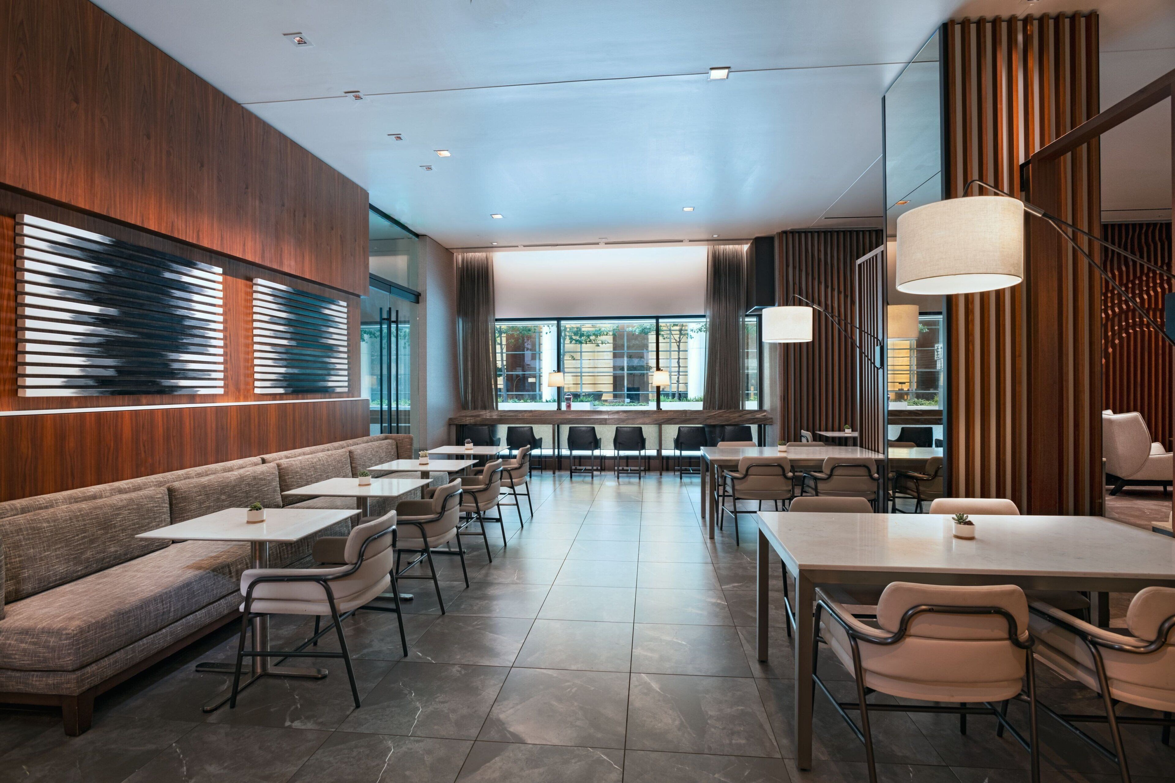 A modern restaurant with a mix of seating options including booths and tables, large windows offering views, and contemporary decor.