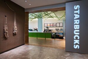A Starbucks store interior with a modern design, including a green counter and a large sign. - AC Hotels by Marriott Houston Downtown (Houston)