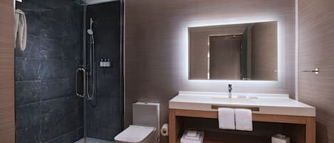 A modern bathroom with a glass-enclosed shower, a toilet, and a vanity with a mirror.