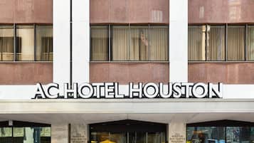 The exterior of the AC Hotel Houston with a clear view of the entrance and the building's facade.