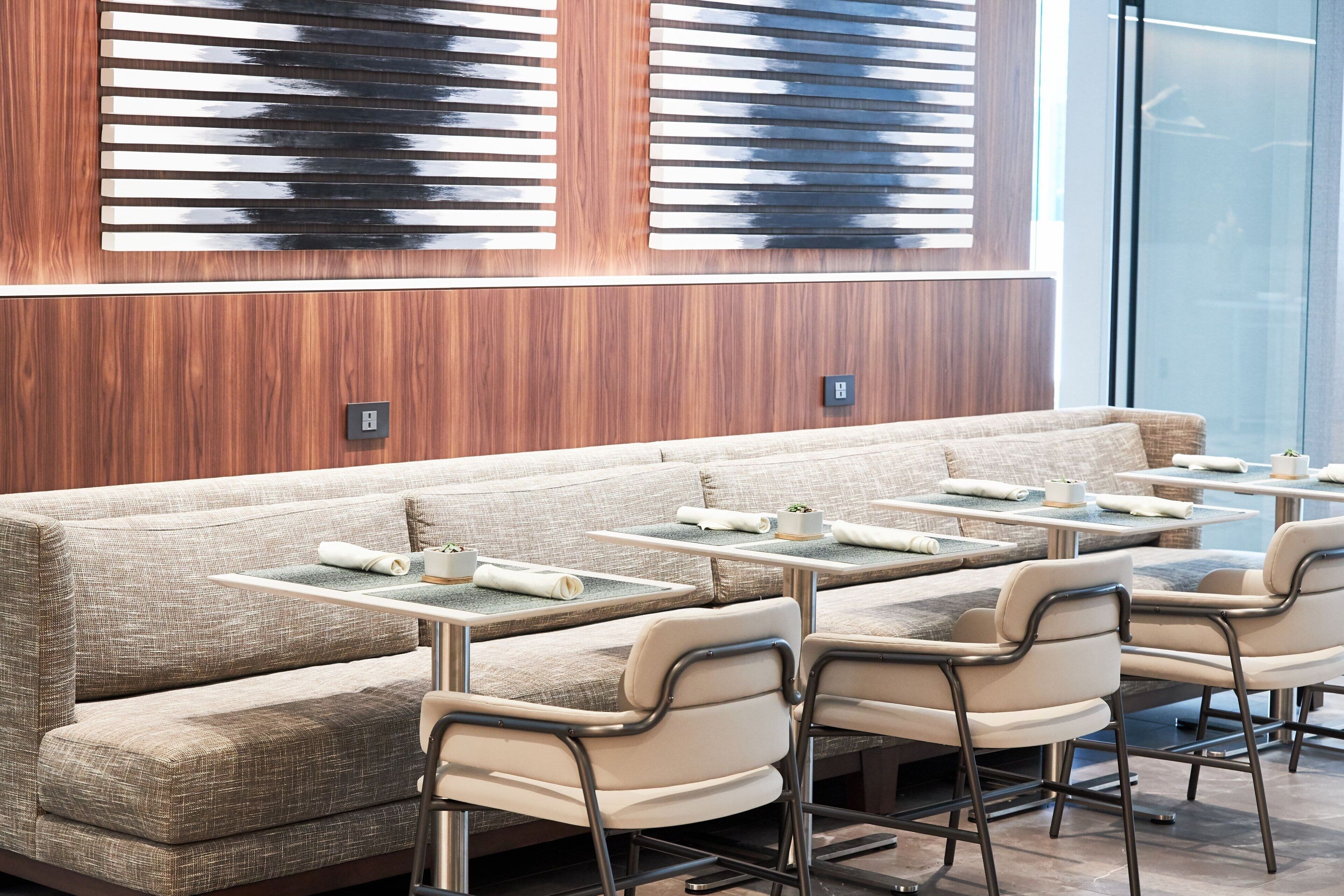 A modern dining area with a long bench and multiple tables, each with a chair.