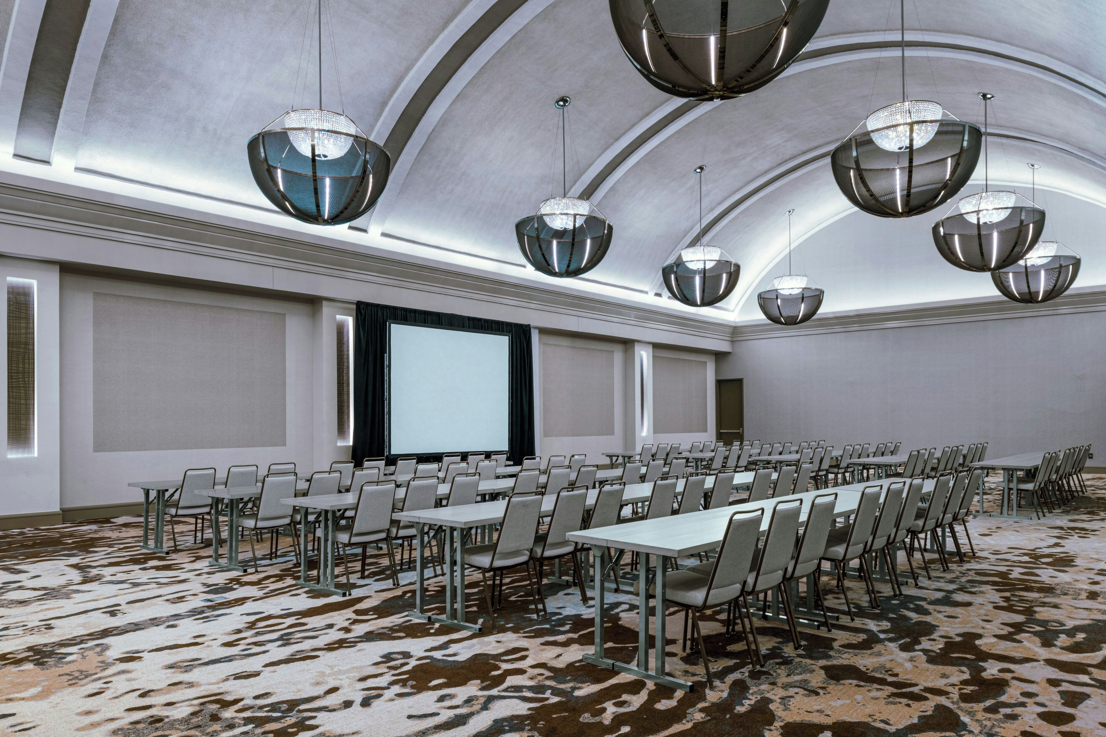 Un sal ón de conferencias con una larga mesa, varias sillas y una pantalla grande.
