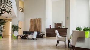 A spacious lobby with a reception desk, seating area, and a staircase. - Aruba Stop Vacation Rentals (Noord)