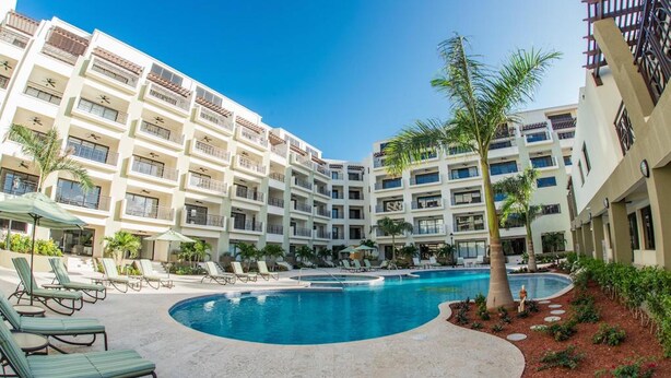 A hotel with a swimming pool, multiple balconies, and lounge chairs. - Aruba Stop Vacation Rentals (Noord)