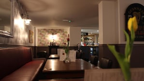 A restaurant interior with a booth seating area, a bar in the background, and a menu stand. - Alcester Inn (Alcester)