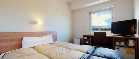 A hotel room with a large bed, a desk with a computer, a television, and a window with a view.