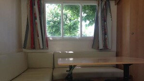 A room with a window, a bench, and two stools. - Camping de Lagraulière (Perpezac-le-Noir)