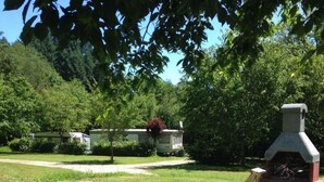 A picnic area with a round table, wooden stumps, and a barbecue grill. - Camping de Lagraulière (Perpezac-le-Noir)