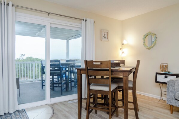 A dining area with a table and chairs, a sliding glass door leading to an outdoor patio, a wall-mounted light fixture, and a framed picture.