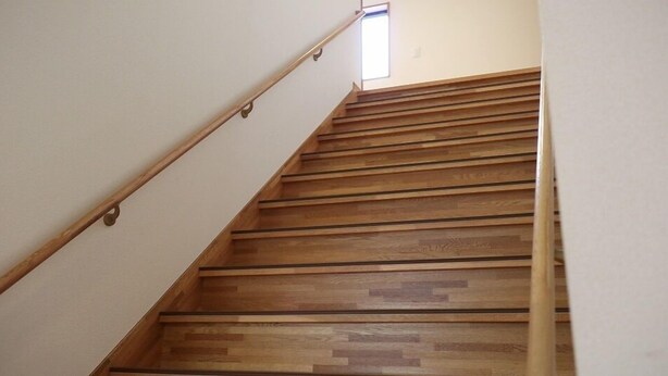 A wooden staircase with a handrail, leading to a landing with a window. - Minshuku Kazu (Kami)