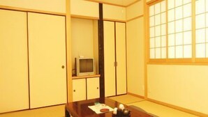 A traditional Japanese room with tatami flooring, a low wooden table, and sliding doors. - Minshuku Kazu (Kami)