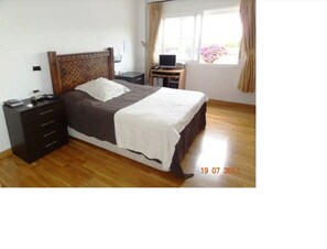 Cozy retreat with a neatly made bed, wooden headboard, and a small desk for work.