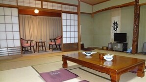 A traditional Japanese room with tatami flooring, a low wooden table, and a television.