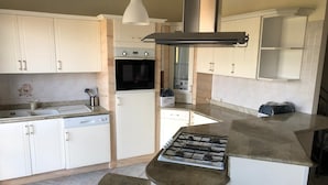 A compact kitchen with white cabinets, a built-in oven, a gas stove, and a sink.