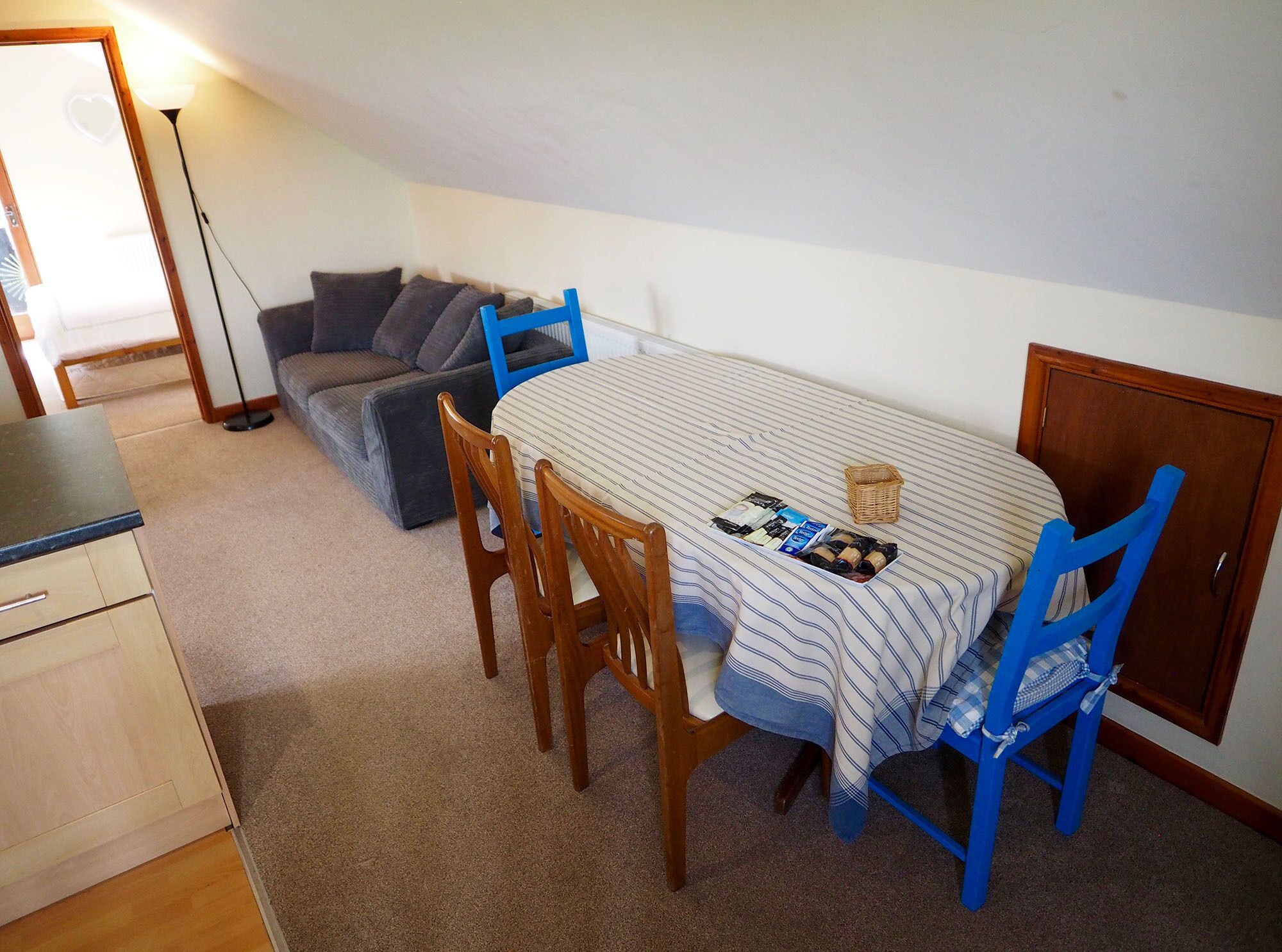 A small dining area with a table set for two, a sofa, and a cabinet.