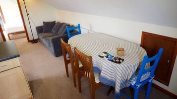 A small dining area with a table set for two, a sofa, and a cabinet.