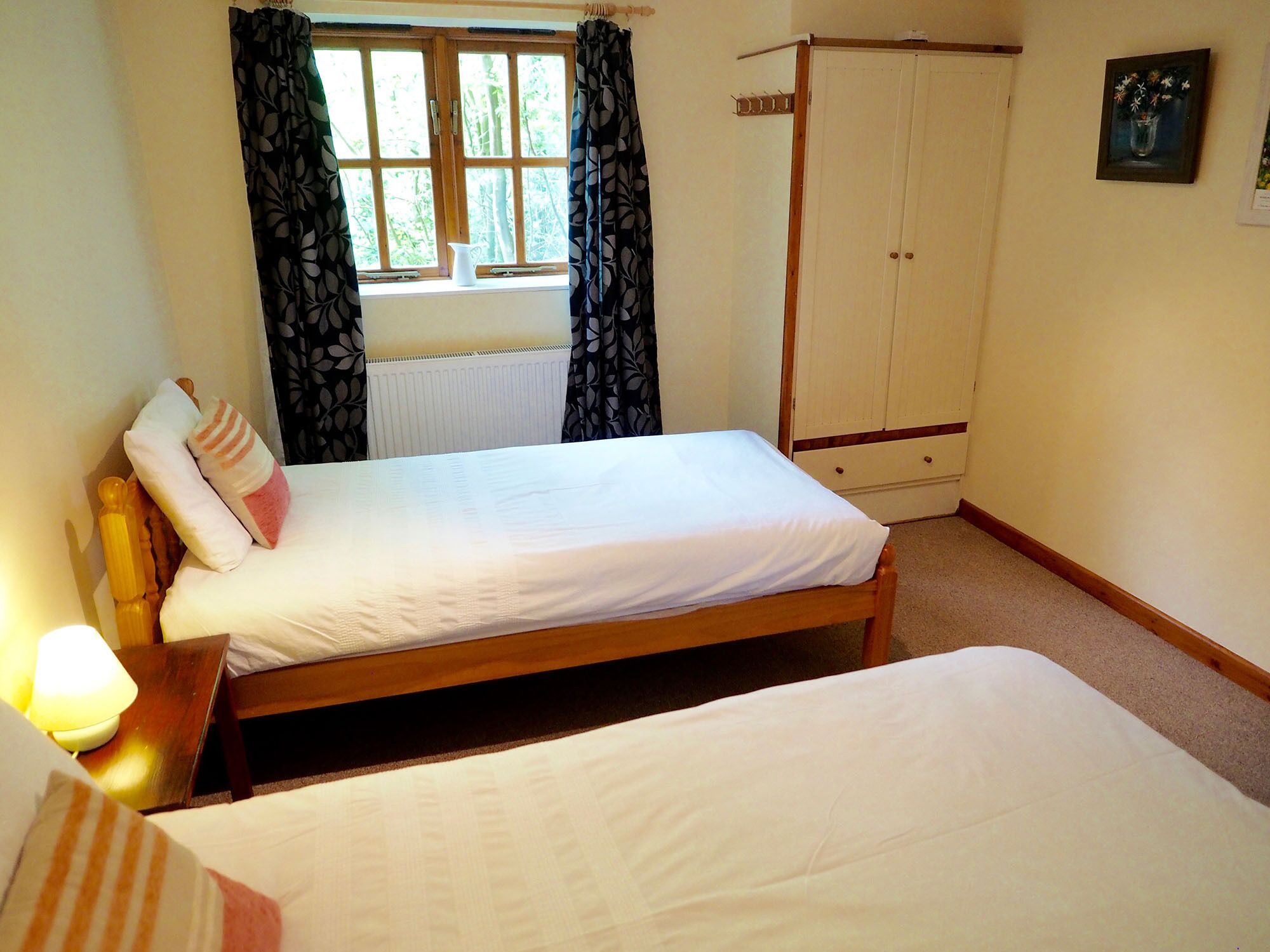 Une chambre avec un lit simple, une armoire et une fenêtre avec des rideaux.