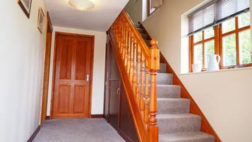 A staircase with wooden balusters and carpeted steps leading to a door.