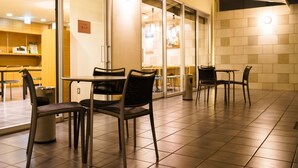 A restaurant with tables and chairs, a trash can, and a tiled floor. - Super Hotel Utsunomiya (Utsunomiya)