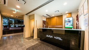 A hotel reception area with a modern design, featuring a reception desk labeled "SUPER HOTEL" and a digital display. - Super Hotel Utsunomiya (Utsunomiya)