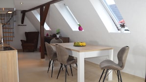 A dining area with a wooden table and four chairs, a staircase, and a skylight. - Wolke65 (Naumburg)