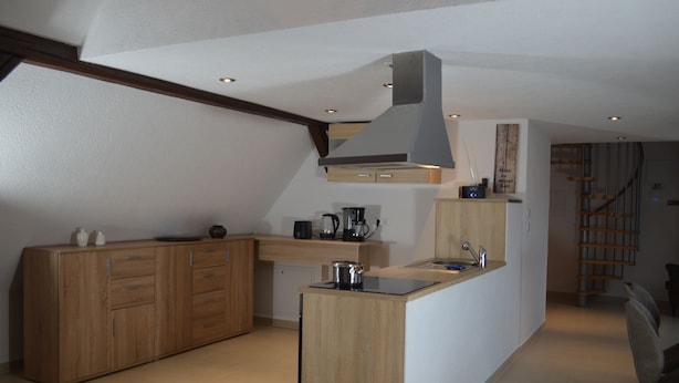 A modern kitchen with wooden cabinets, a central island, and a built-in stove. - Wolke65 (Naumburg)