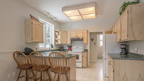 Una cocina con armarios de madera, una isla central con taburetes de bar y un ventanal que proporciona luz natural.