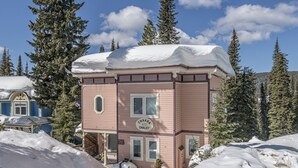 Un edificio rosa con un letrero que dice "Chakra 170 Chalet", rodeado de nieve y árboles.