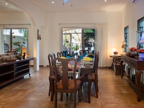 A dining area with a long table set for multiple people, surrounded by chairs.