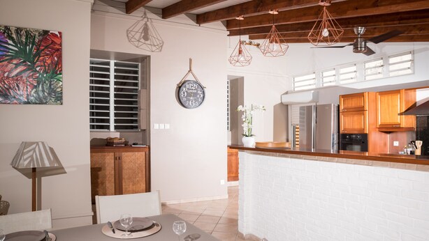 Une cuisine moderne avec des murs en briques blanches, des poutres en bois au plafond et des luminaires suspendus.