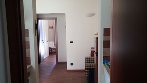 Un pasillo con un tapete de cuadros, una puerta y una pequeña mesa con una silla.