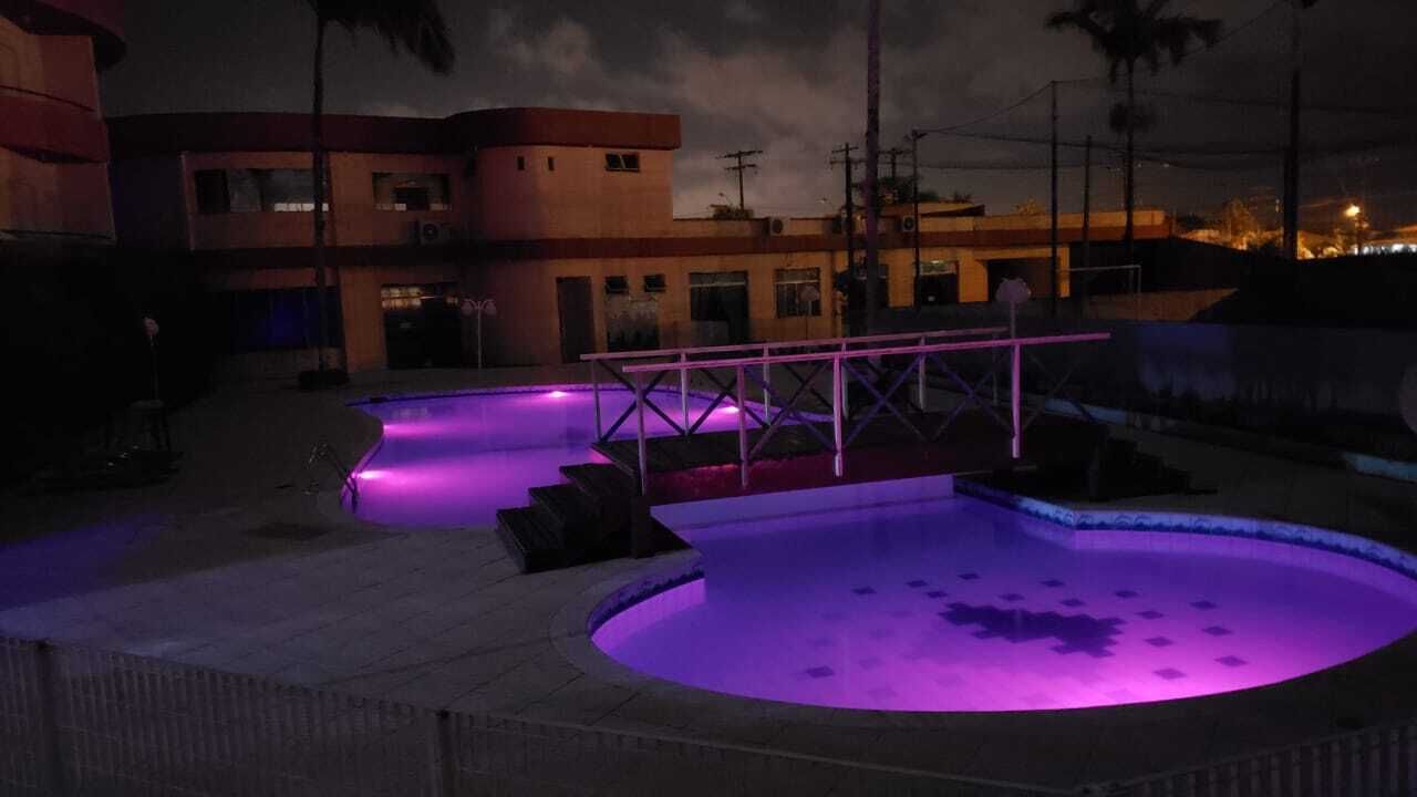 En pool med en metallkonstruktion i mitten, omgiven av en låg mur och ett stenlagt område.