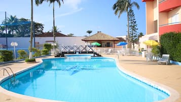 Una piscina al aire libre, sombrillas, sillones reclinables de piscina