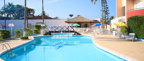 Una piscina al aire libre, sombrillas, sillones reclinables de piscina