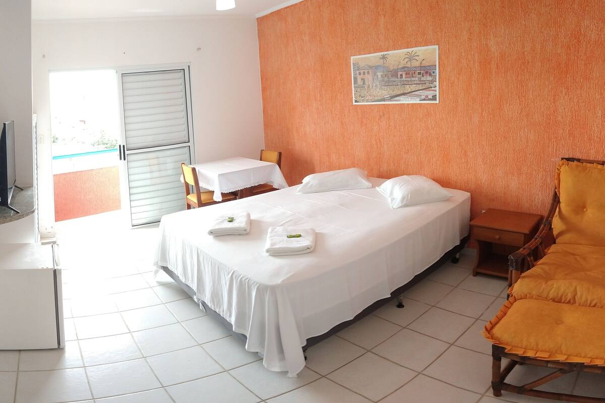 Une chambre d’hôtel avec un lit, une chaise, une table et un téléviseur.