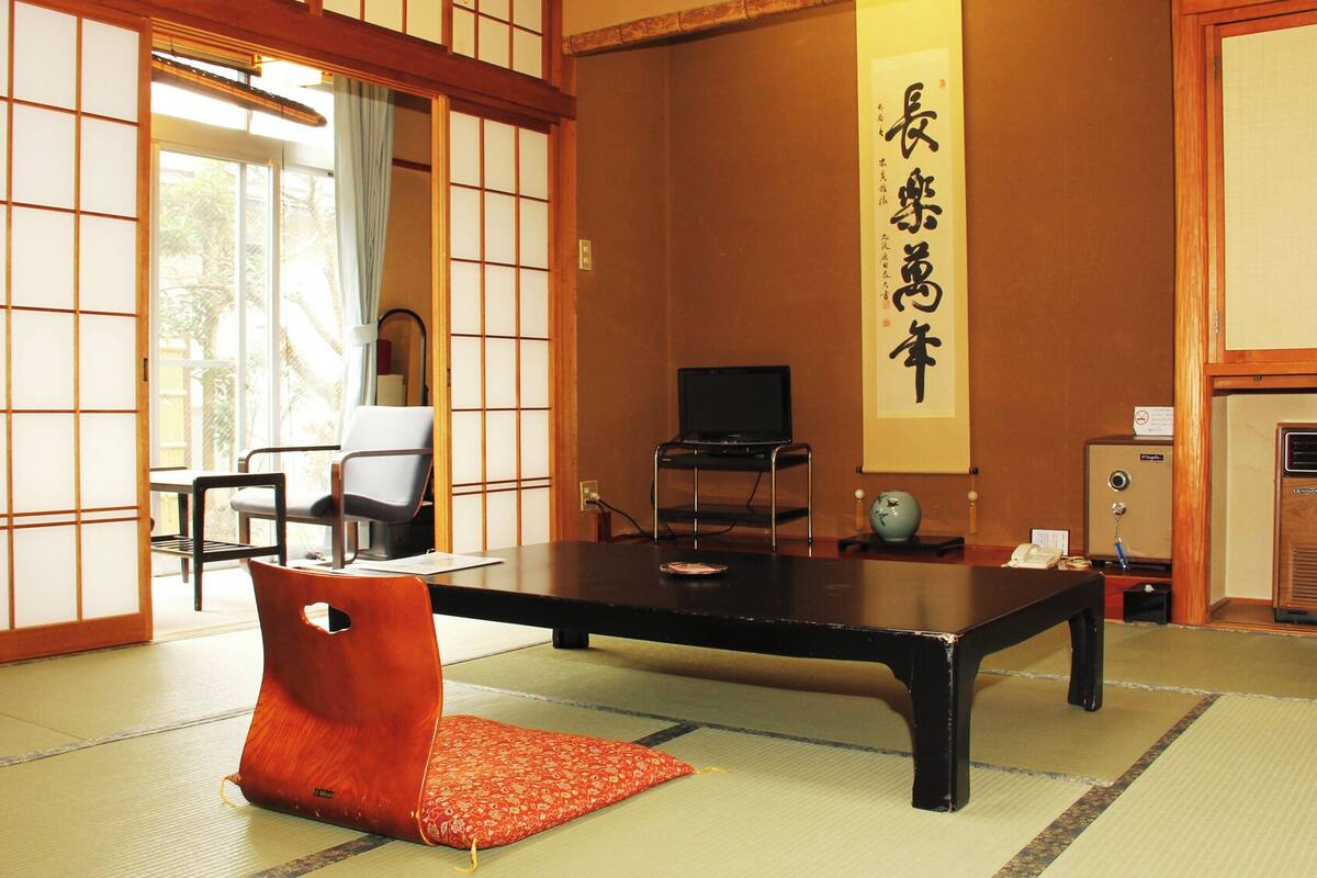 Een traditionele Japanse kamer met tatami vloerbedekking, een lage tafel, een televisie en een shoji schuifdeur.