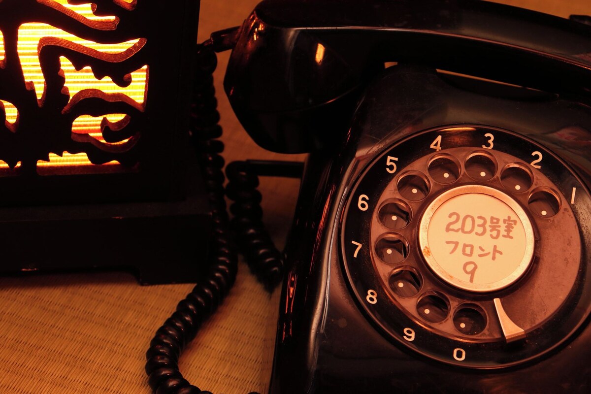 En telefon med vridskiva, en rund nummerskiva och en etikett med japanska tecken.